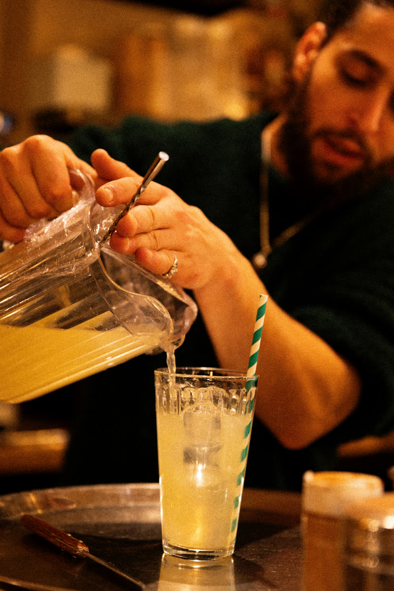 Barman versant une limonade dans un verre glacé, au comptoir