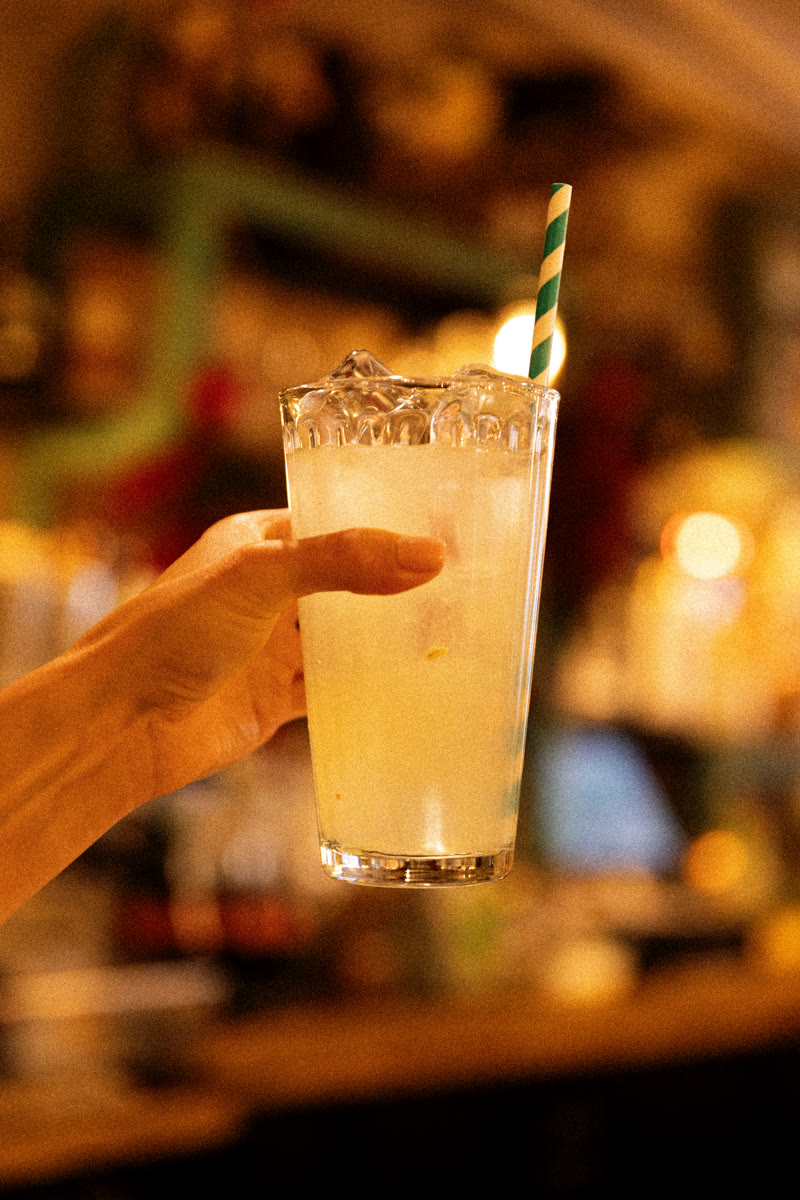 Main saisissant un verre de limonade à la paille rayée, au bar