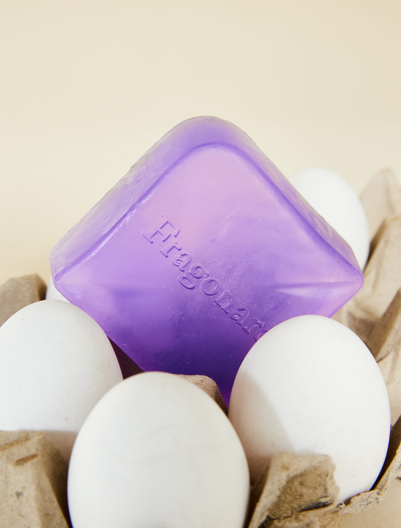 Savon translucide violet calé entre des œufs blancs dans une boîte à œufs