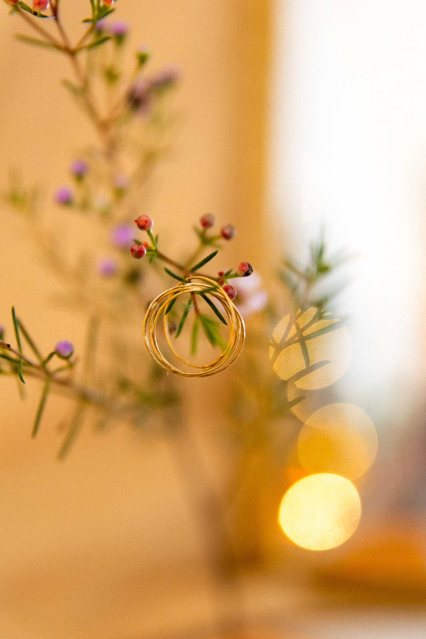 Anneaux dorés suspendus à une branche fleurie, arrière-plan en bokeh doré