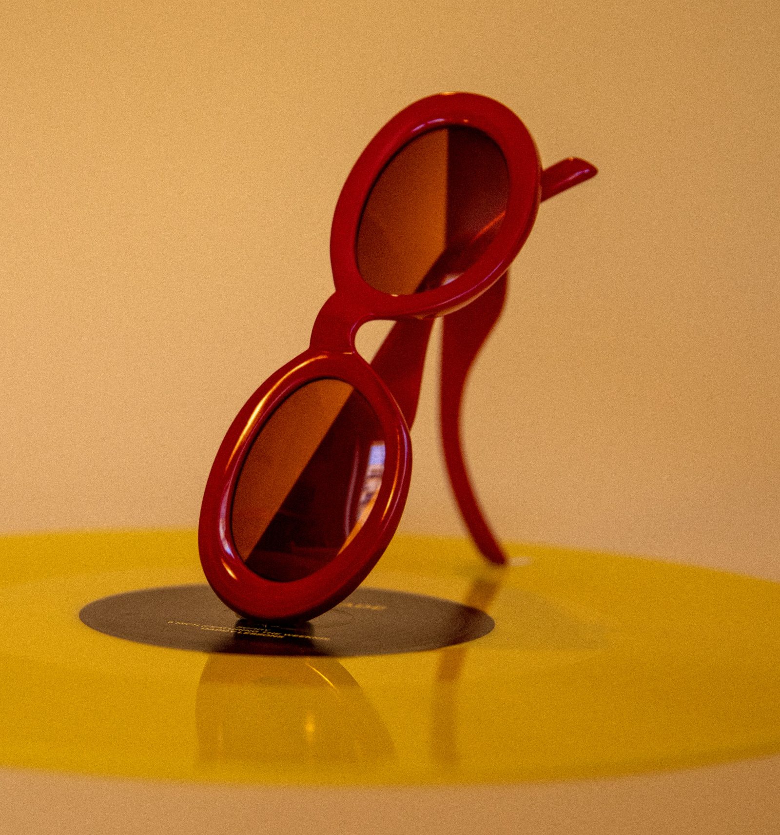 Lunettes de soleil rouges dressées sur un disque jaune, ombre portée